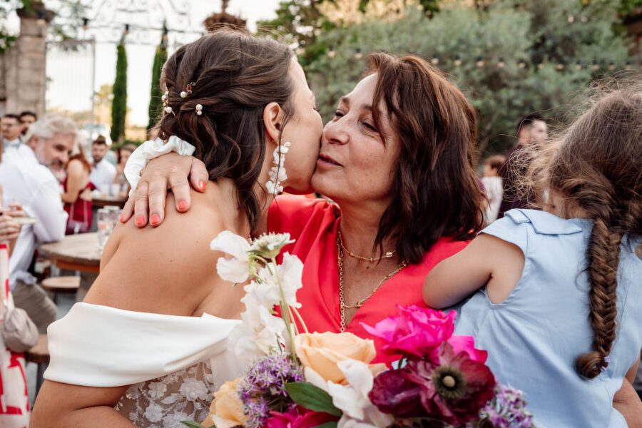 Mariée qui embrasse une invitée avec son bouquet coloré – mariage dans l’Hérault